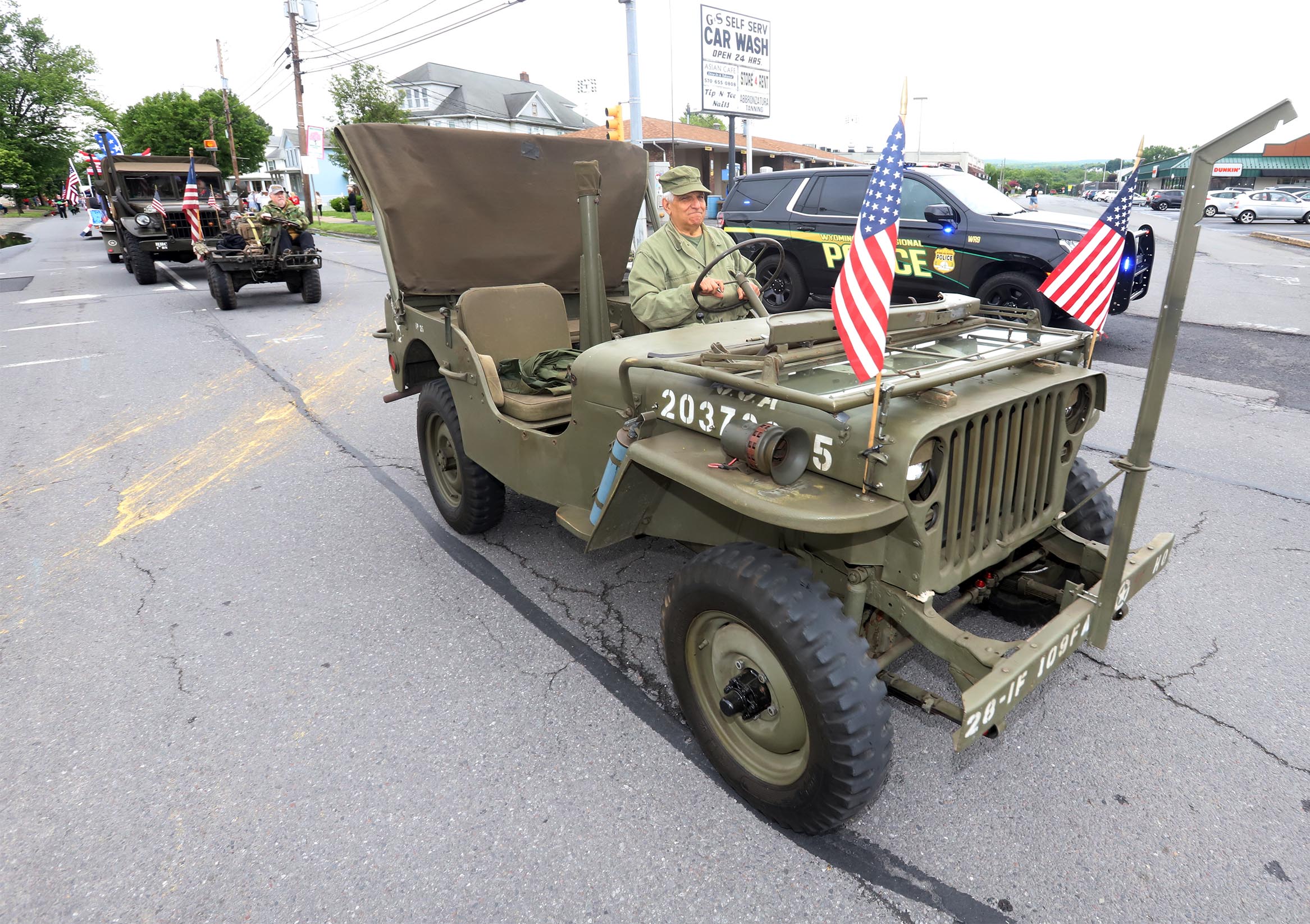 Vintage military vehicles make their way along Wyoming Avenue during...