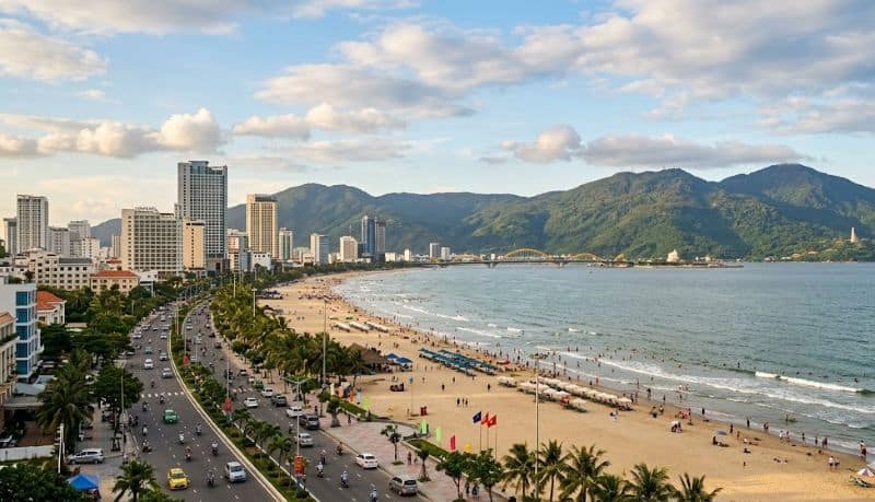Beach and cityscape of da nang, vietnam, with mountains in the background.