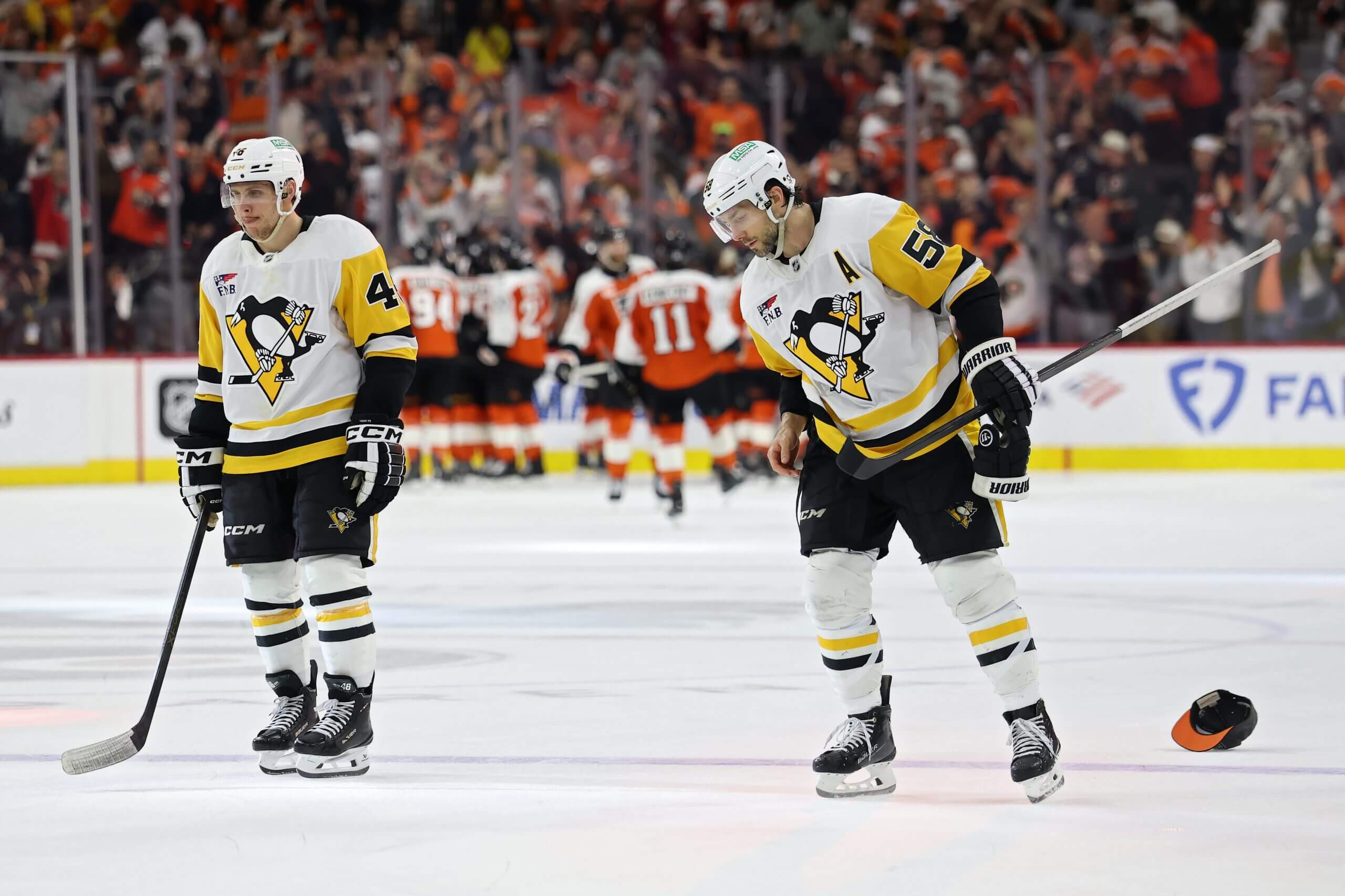 Lizotte and Letang skate off the ice after their season ended, as the Flyers celebrate in the background