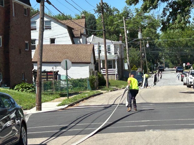 Firefighters and helpers extend hoses up Andrews Avenue as crews needed more water for the fire. (PETE BANNAN-DAILY TIMES)