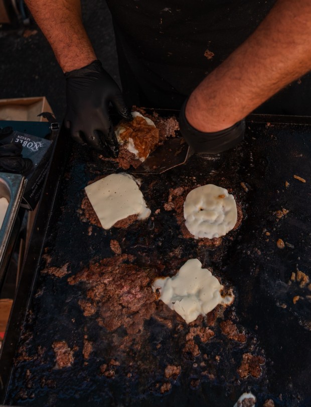 Juny Gonzalez of Louie's Kitchen and Bar cooks up burgers during the Taste of Hamburg-er Festival in downtown Hamburg on Aug. 30, 2025. (MATTHEW PERSCHALL/MULTIMEDIA EDITOR)