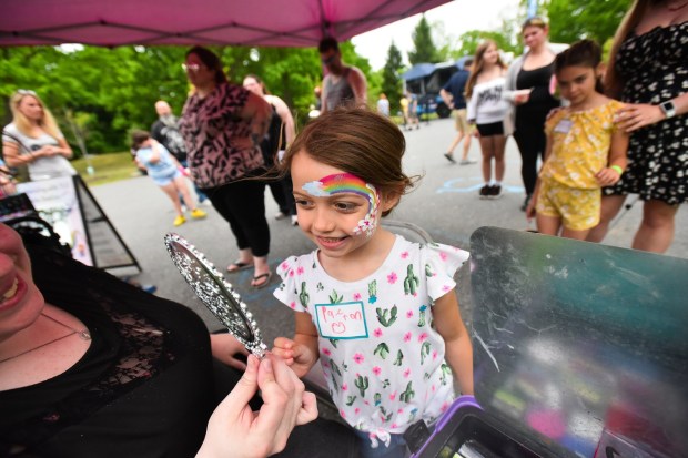 Payton Giberson, 5, of Scranton, looks at her new face paint done by Sweet Cheeks owner Megan Fenwick during the Scranton Cyber Academy picnic at Nay Aug Park in Scranton Wednesday, May 27, 2026. (SEAN MCKEAG / STAFF PHOTOGRAPHER)