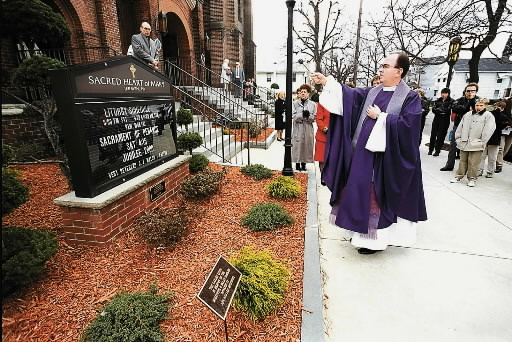 The Rev. James J. Walsh blesses a new sign with...