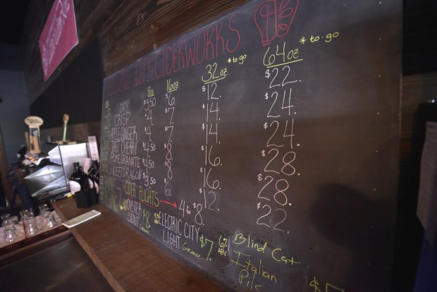 A menu of options displayed on a chalklboard is shown at Electric City Ciderworks on Linden Street in Scranton opened in April. Three brothers, Tom, left, Alex, middle, and Mike Borthwick, transformed the downtown property into a new cidery while preserving some of the city's past in the process. (CHAD SEBRING/STAFF PHOTO)