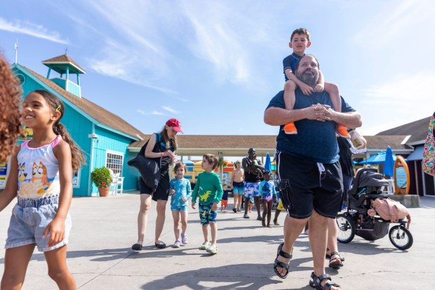 Families walk to a cove for the swimming lesson Thursday, June 20, 2024, during the 15th annual World's Largest Swimming Lesson at Dorney Park & Wildwater Kingdom in South Whitehall Township. Dorney Park joined hundreds of aquatic centers across the nation to promote the importance of water safety and swimming skills in partnership with the Boys & Girls Club of Allentown and Swim-in Zone. (Emma Reed/The Morning Call)