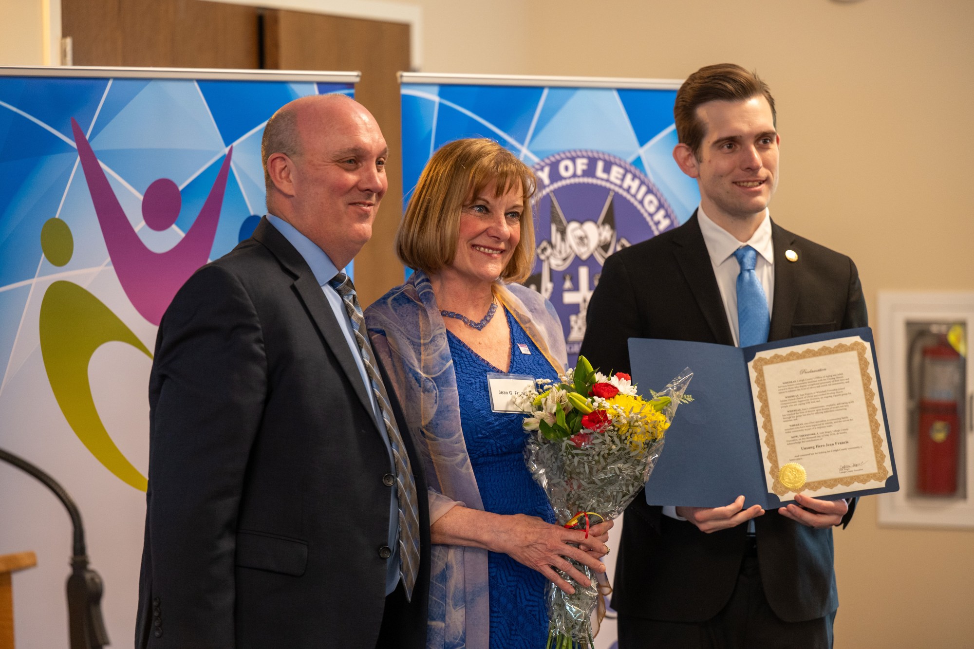 JR Reed of Lehigh County Aging & Adult Services and Lehigh County Executive Josh Siegel present an award to Jean Francis of Whitehall Township during the 26th annual Unsung Heroes tribute Wednesday, May 13, 2026, at Fellowship Community's Zentz Center in Whitehall Township. Francis organizes a grief support group at Jordan United Church of Christ. The annual tribute recognizes older adults who have enhanced their communities through active engagement, volunteerism and service to others. (Jonathan Broady/Special to The Morning Call)