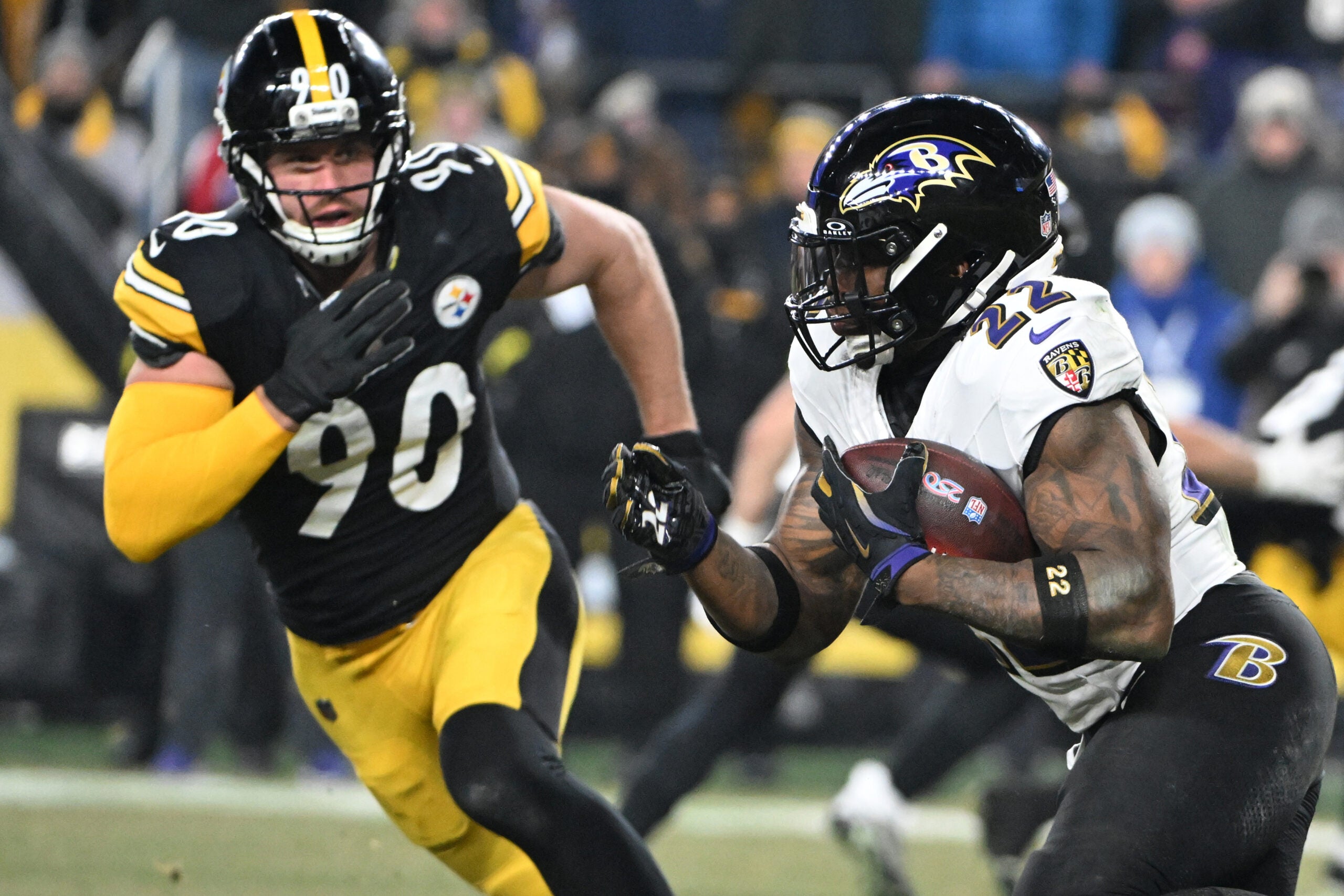 Jan 4, 2026; Pittsburgh, Pennsylvania, USA; Baltimore Ravens running back Derrick Henry (22) rushes the ball past Pittsburgh Steelers linebacker T.J. Watt (90) during the first half at Acrisure Stadium.