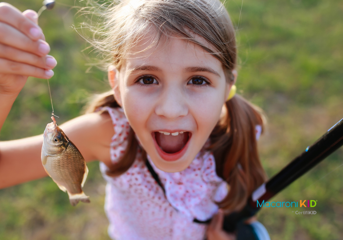 little girl holding. up small fish to the camera