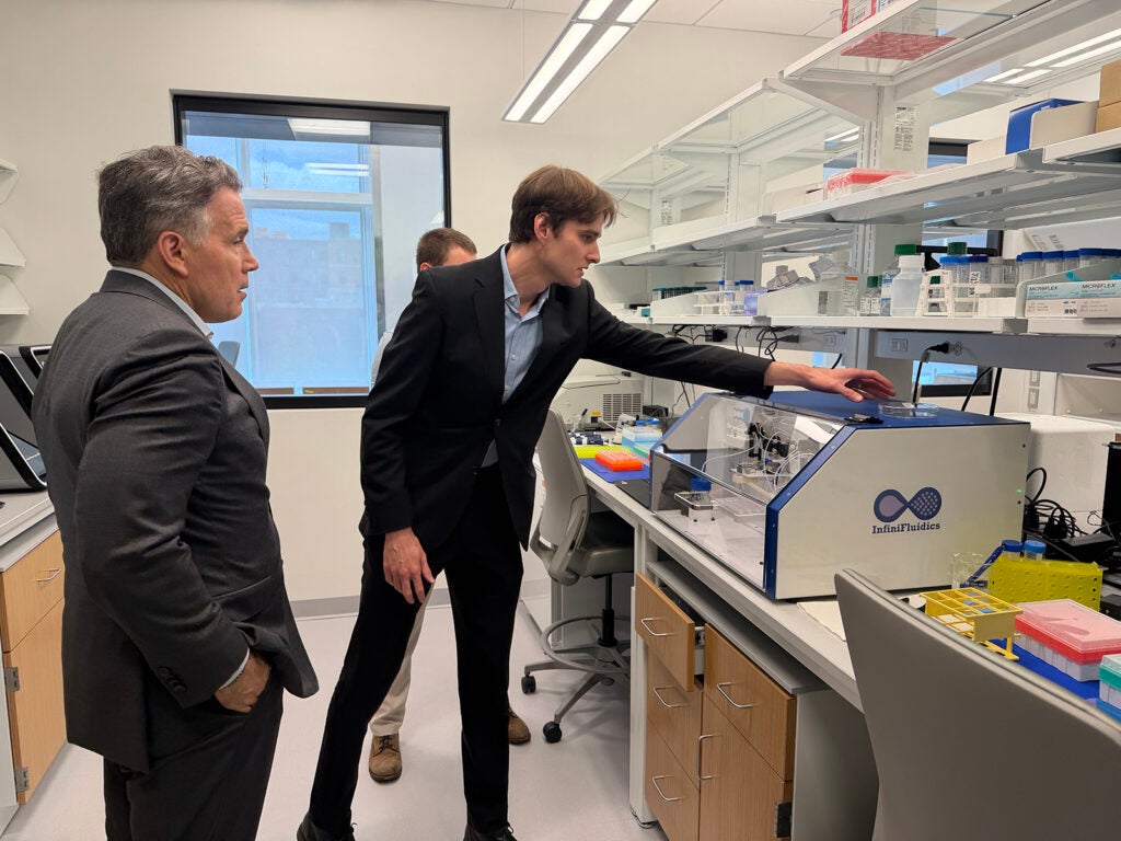 A man reaches for a piece of technology while touring the University of Pennsylvania's AIRFoundry with Senator Dave Mccormick.