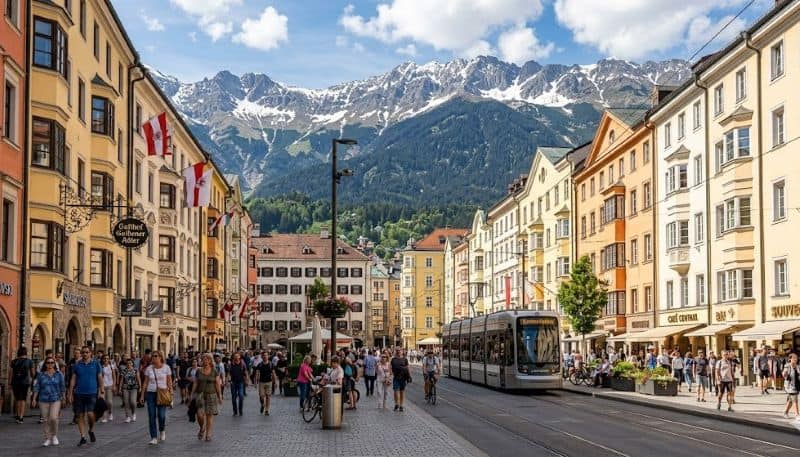 Mountain view village with tram in a european town, alps backdrop.
