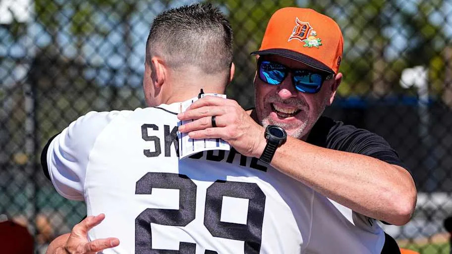 Detroit Tigers pitcher Tarik Skubal wearing white uniform hugs Triple-A Toledo hitting coach Mike Hessman wearing orange hat.