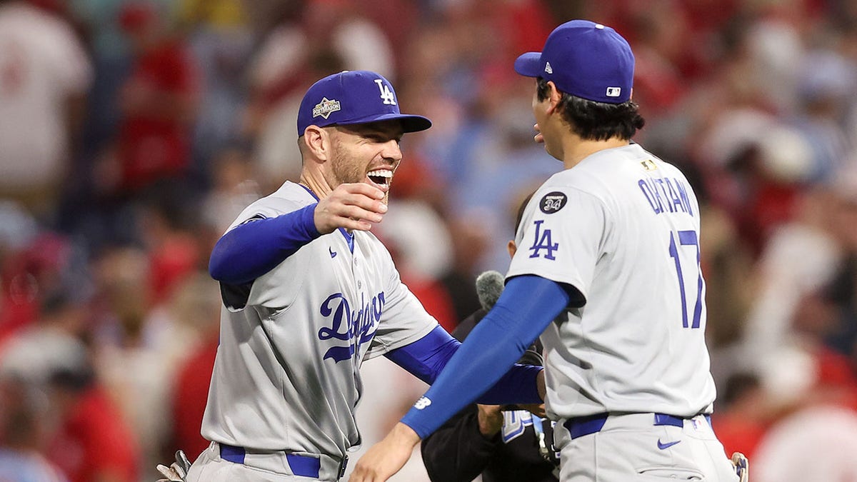 Los Angeles Dodgers first baseman Freddie Freeman and designated hitter Shohei Ohtani hugging on baseball field