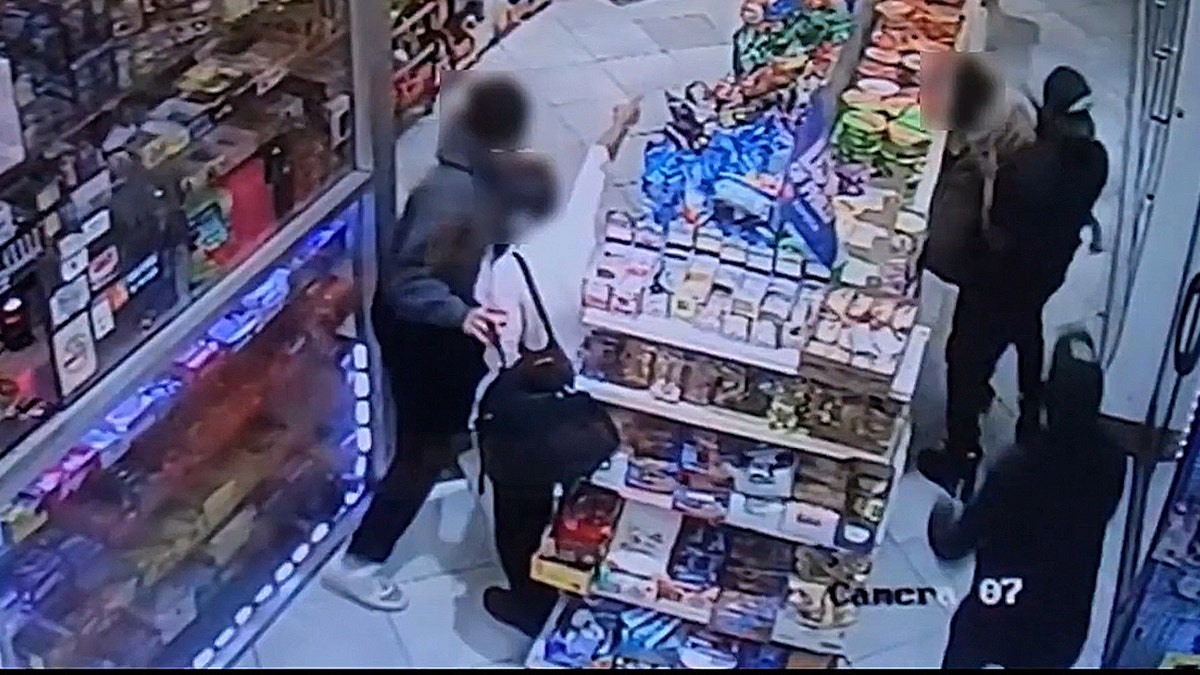 Surveillance footage shows several individuals standing near snack displays inside a brightly lit convenience store.