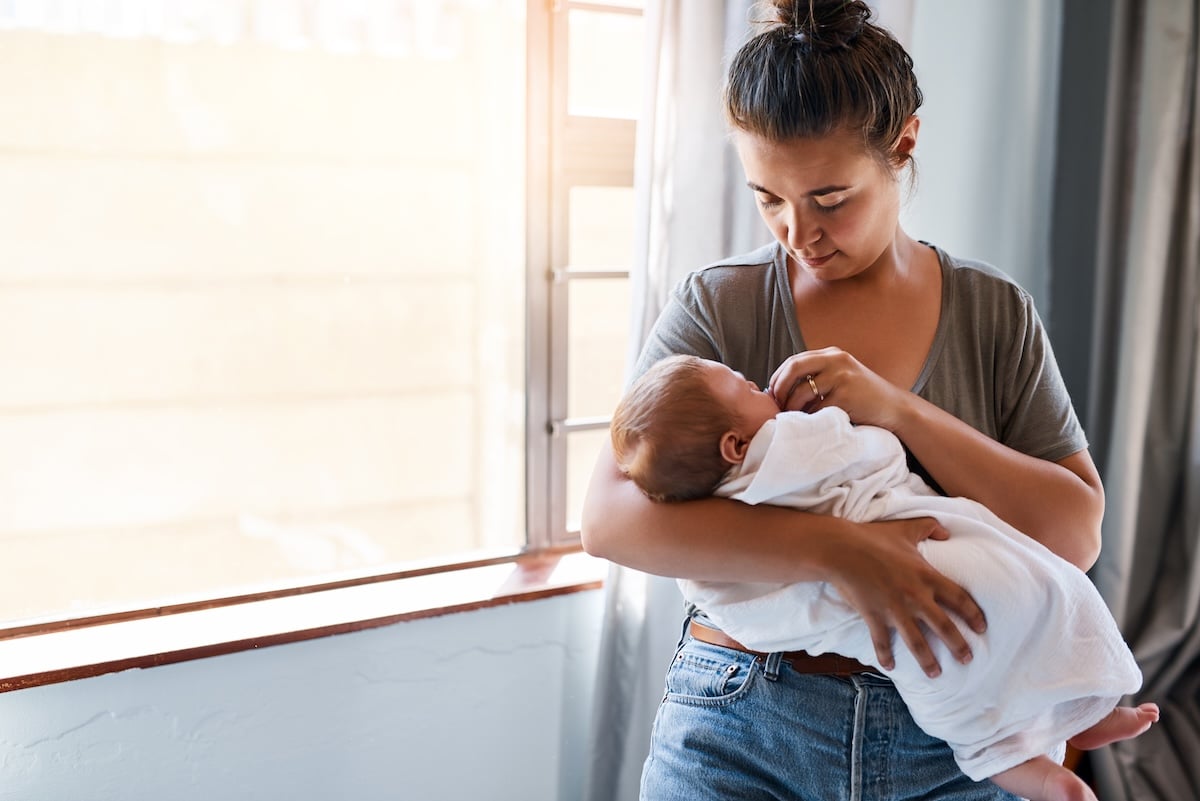 Mother holds her baby gently while smiling down at them.