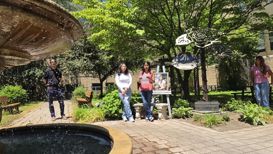 Janellyn Alonso Perez and Allison Juarez speak about their friend, Rose Hernandez. To the left, behind fountain, is teacher Ryan Hnat.
