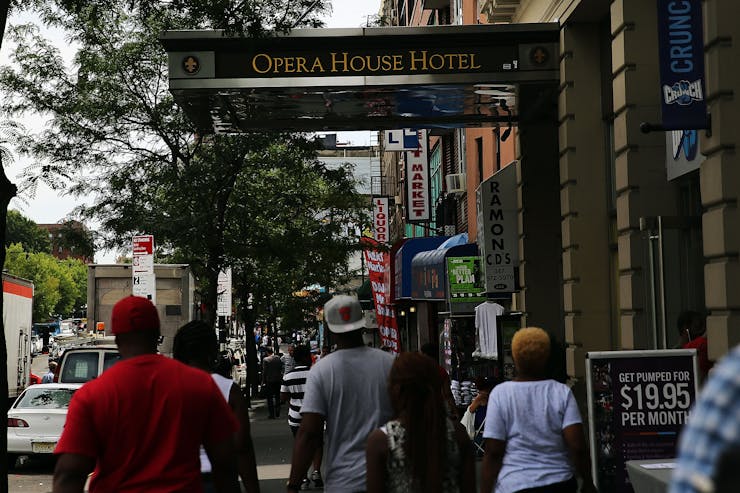 People walk down street near building that says Opera House Hotel