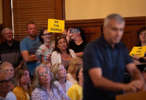 Olyphant resident Eva Rappenglueck, a core member of the Stop Olyphant Data Center movement, holds a "We the People" sign and reacts to public comment during a council meeting in the Municipal Building in Olyphant on Tuesday, June 9, 2026. (FRANK WILKES LESNEFSKY / STAFF PHOTO)