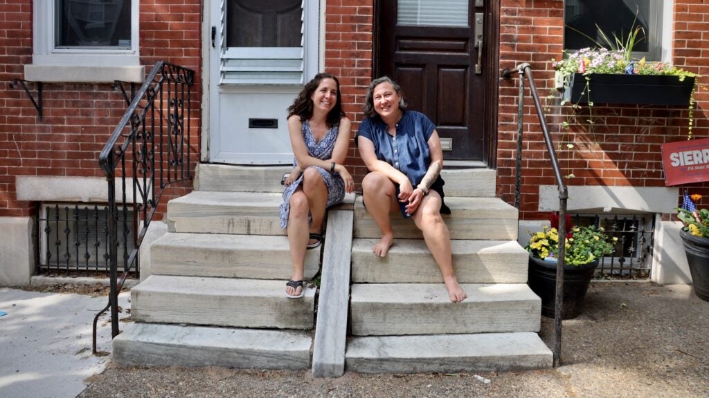 Nina Hernandez and Nicole Ross pose for a photo while sitting on their front steps.
