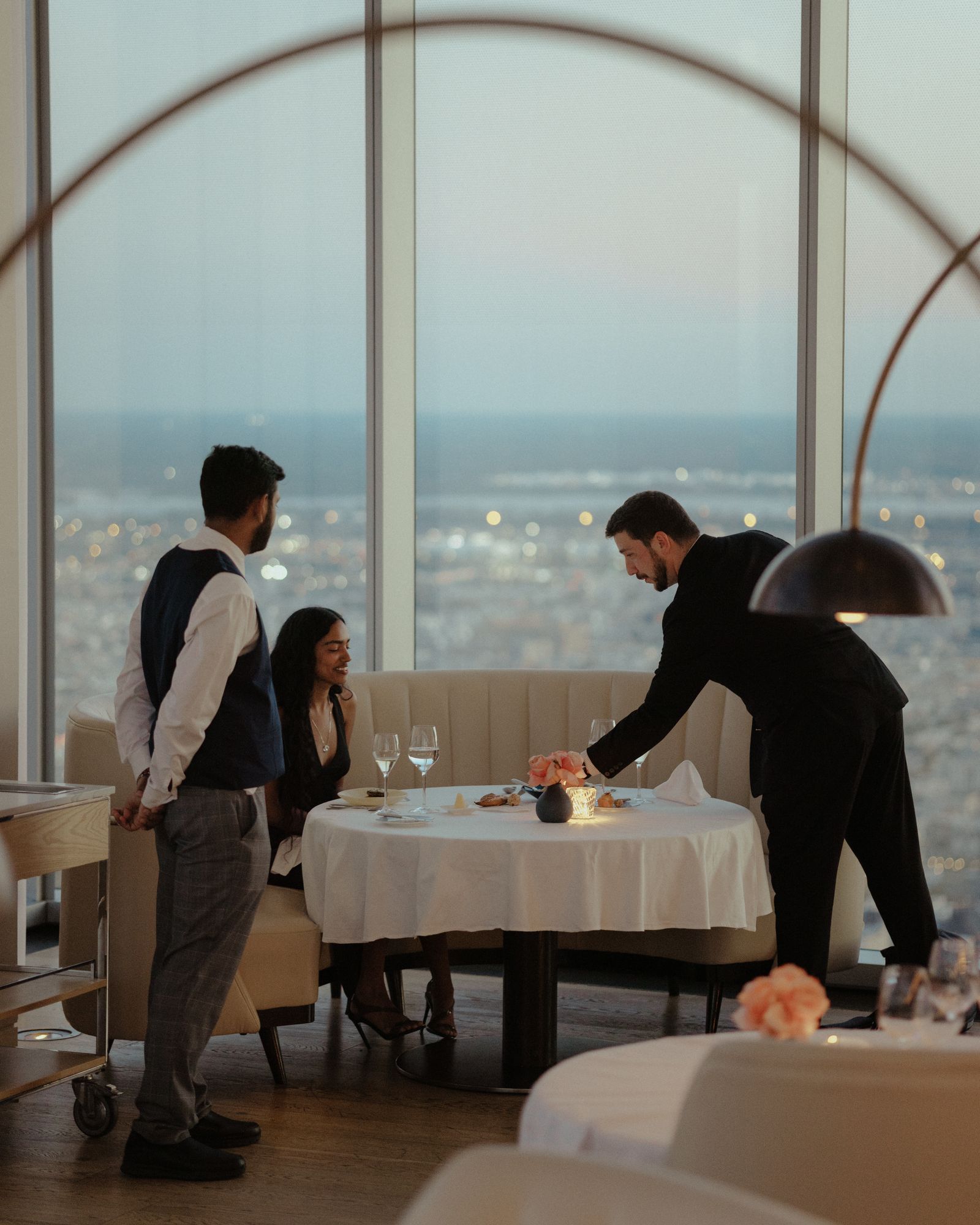 A waiter handing over some plates and drinks to patrons at a table