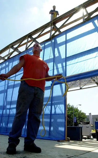 City of Erie employee Dennis Kuhar, bottom, helps city carpenter Mike Bisbee rig the main stage at We Love Erie Days on Aug. 15, 2001.