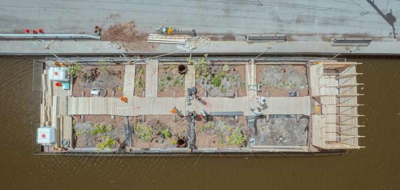 An aerial view of a barge with a walkway and plant life on it.