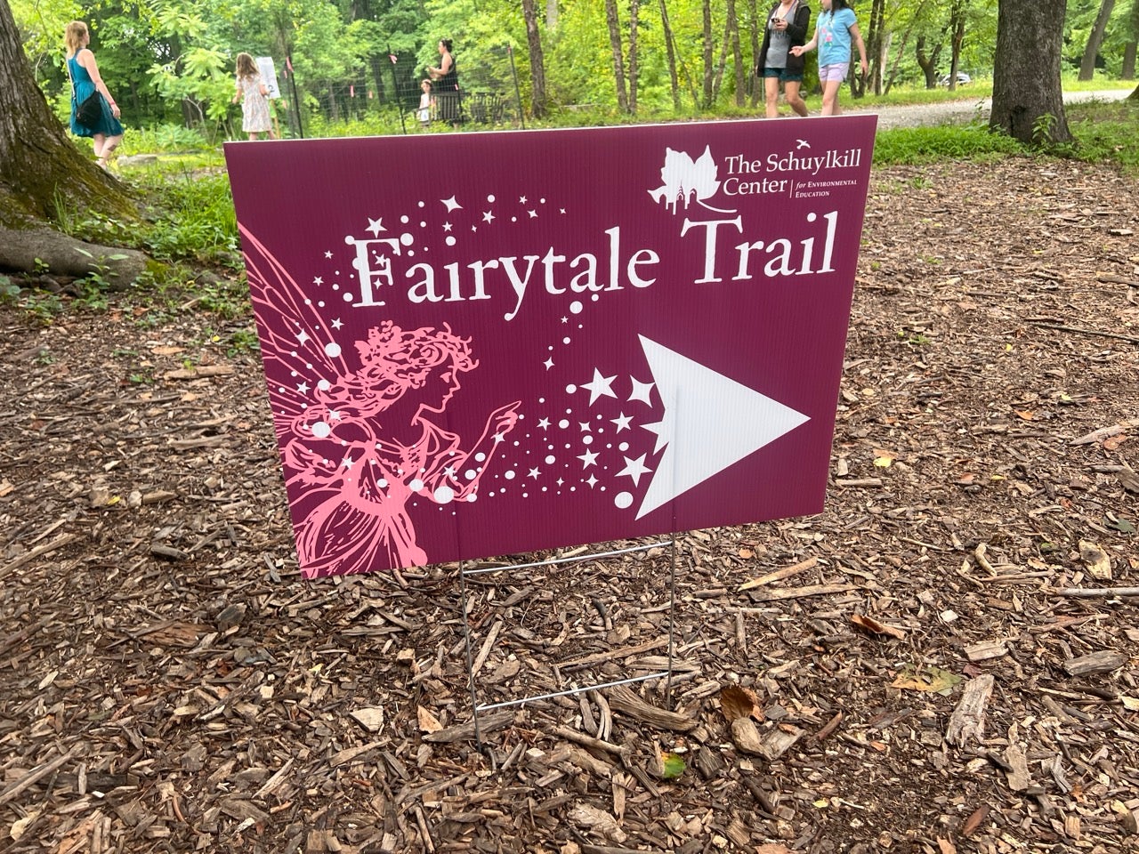 Philadelphia Fairy Festival pink Fairytale Trail sign in the woods with an arrow pointing to the right.