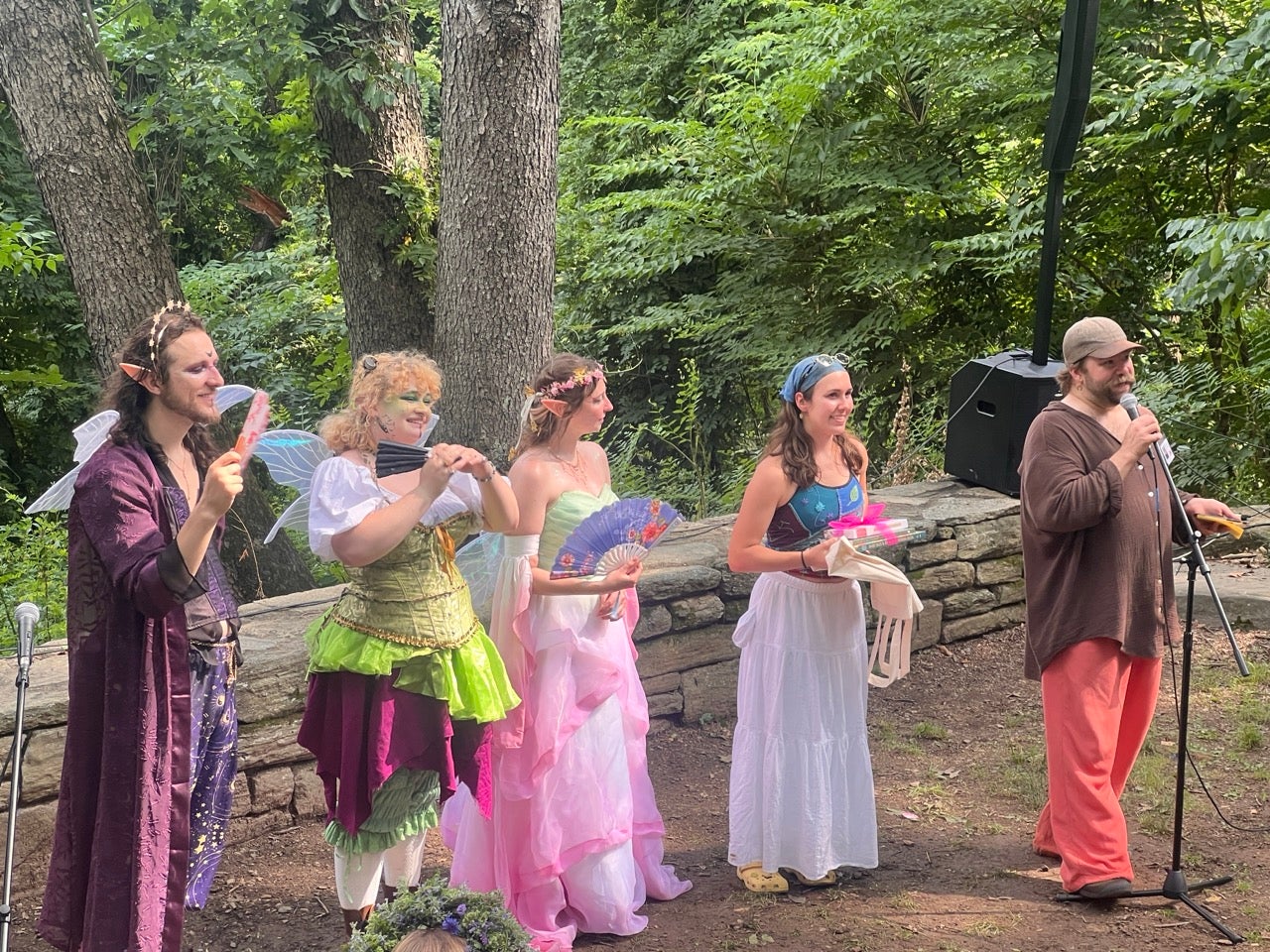 The Philadelphia Fairy Festival organizers all dressed up as fairies and for the occasion present the winning Fairy House artist with her prize. She is in the white skirt with blue bandana in her hair.