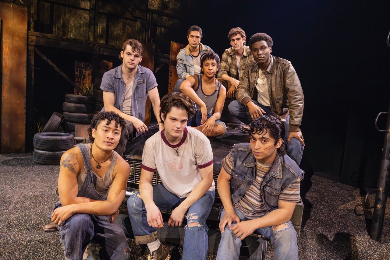 8 young 'Greasers" pose for a photo in jeans and jean jackets with serious looks on their faces in The Outsiders The Musical North American Tour.