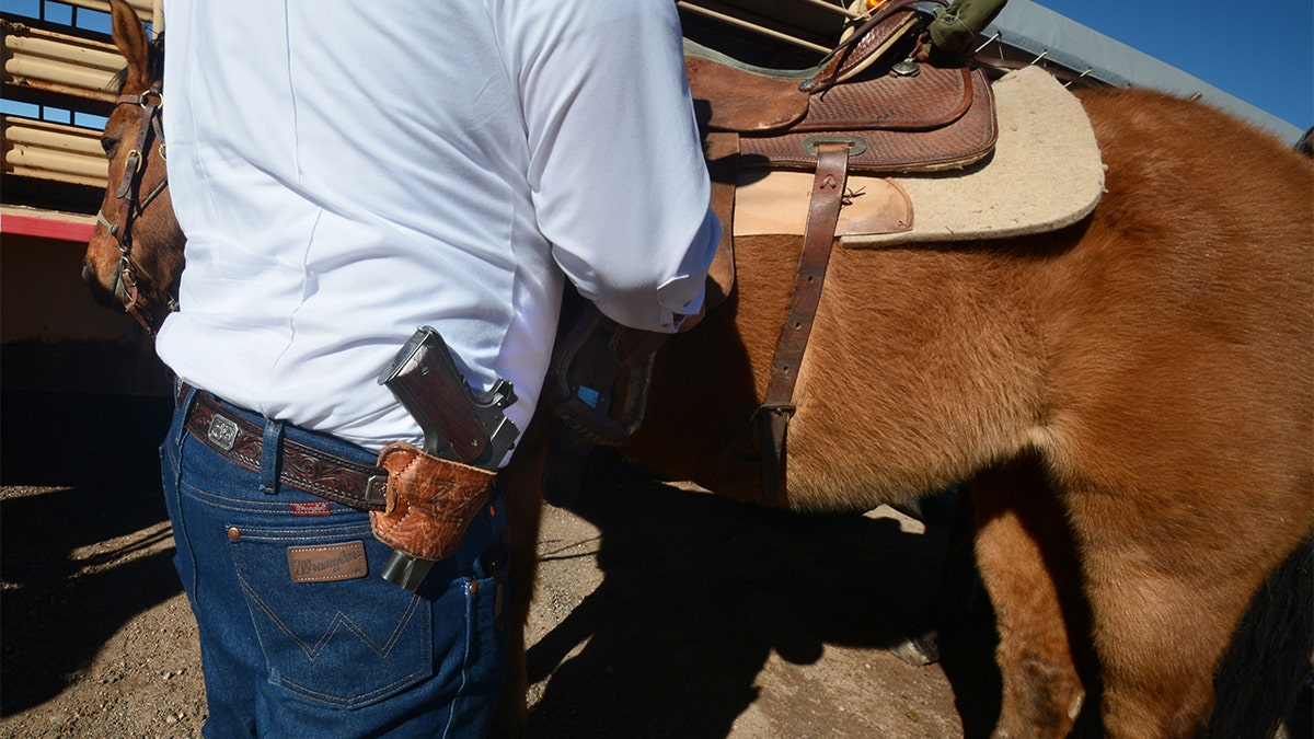 An armed member of Cowboys for Trump leading horse-mounted supporters through downtown Santa Fe streets