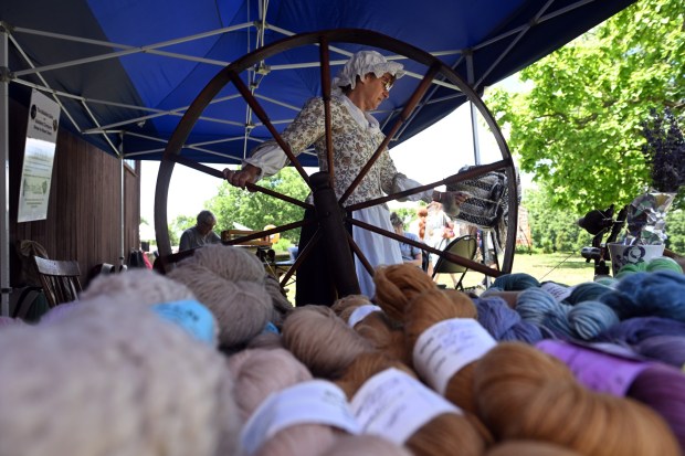 Margi Wright of Hamburg operates a great wheel from the late 1700s to spin wool during Americana Fest. (BILL UHRICH/READING EAGLE)