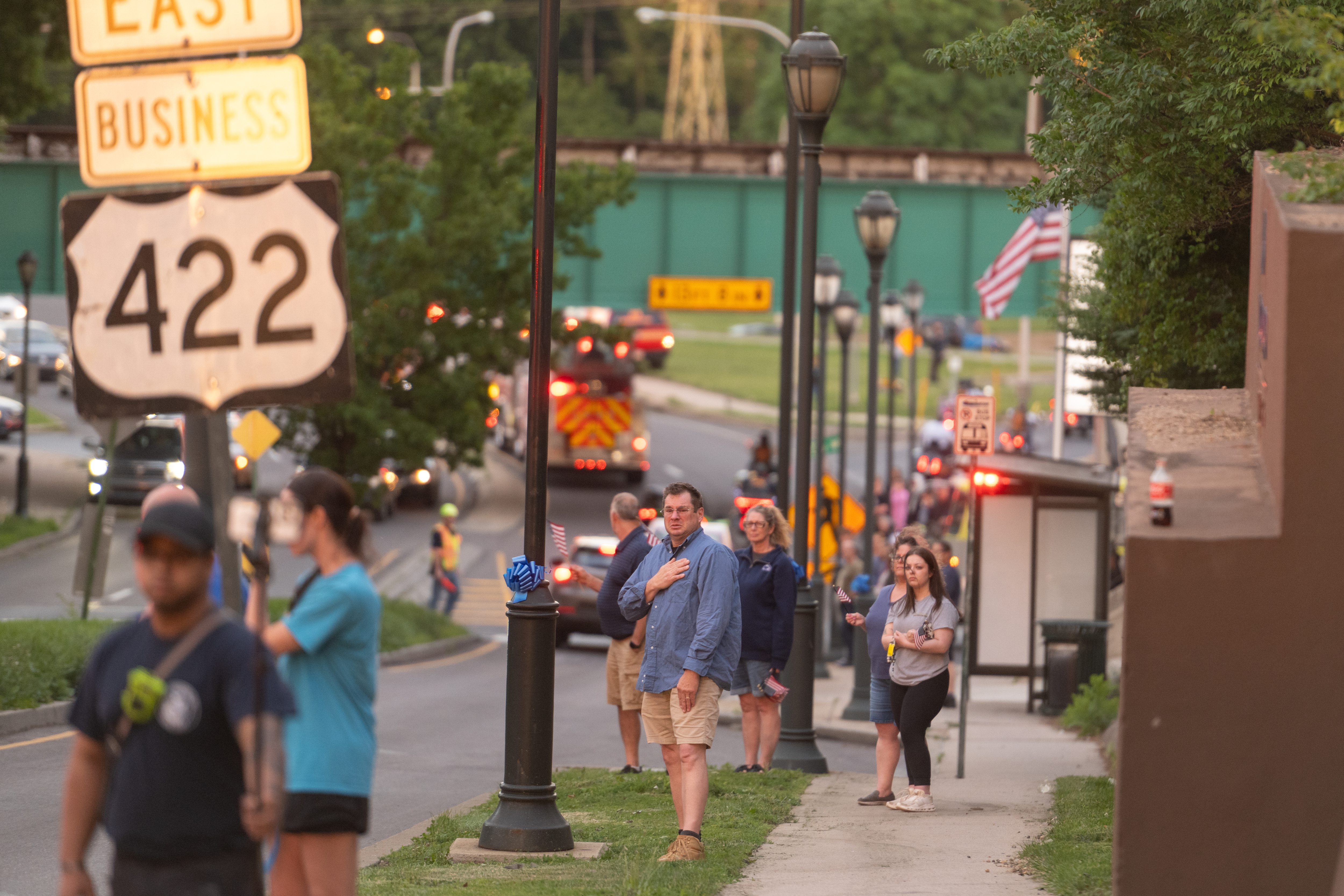 Community members watch and salute by the side of Penn...