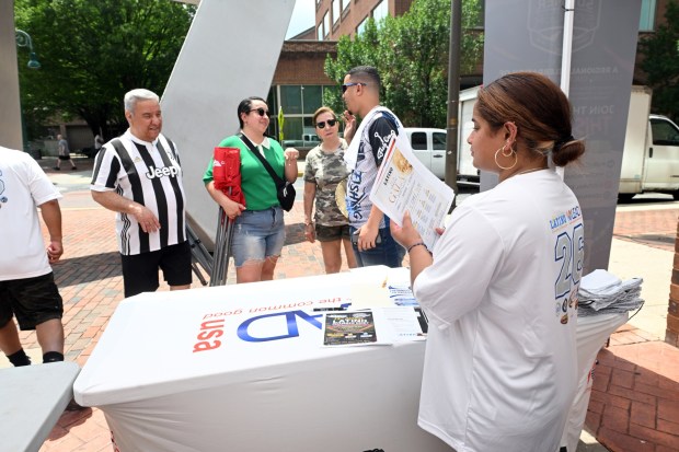 Elma Urena passes out adult education information during a World Cup Soccer watch party held in the courtyard in the 600 block of Court Street as fans watched the Mexico against South Africa match. (BILL UHRICH/READING EAGLE)
