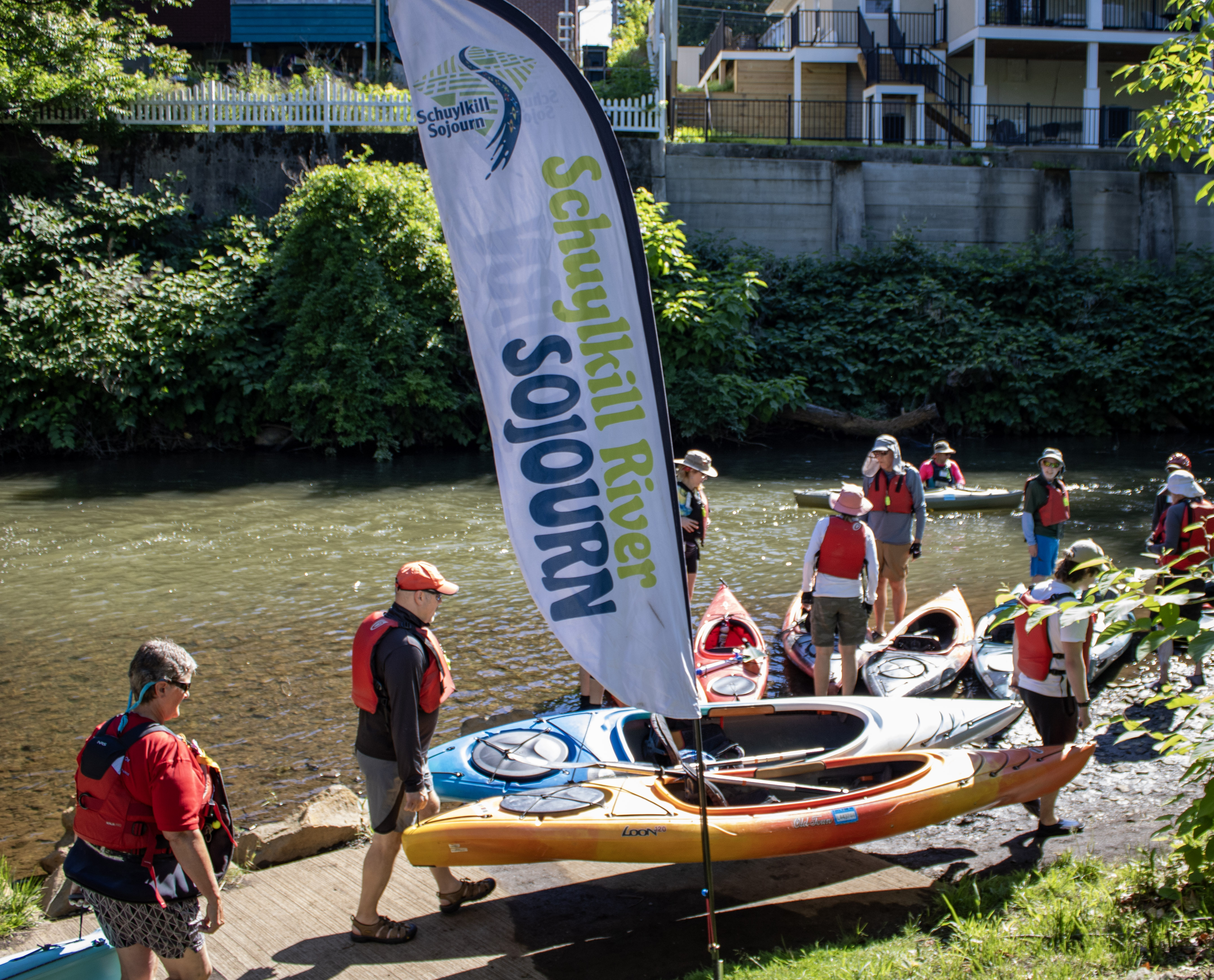 Paddlers carry their kayaks toward the Schuylkill River as the...
