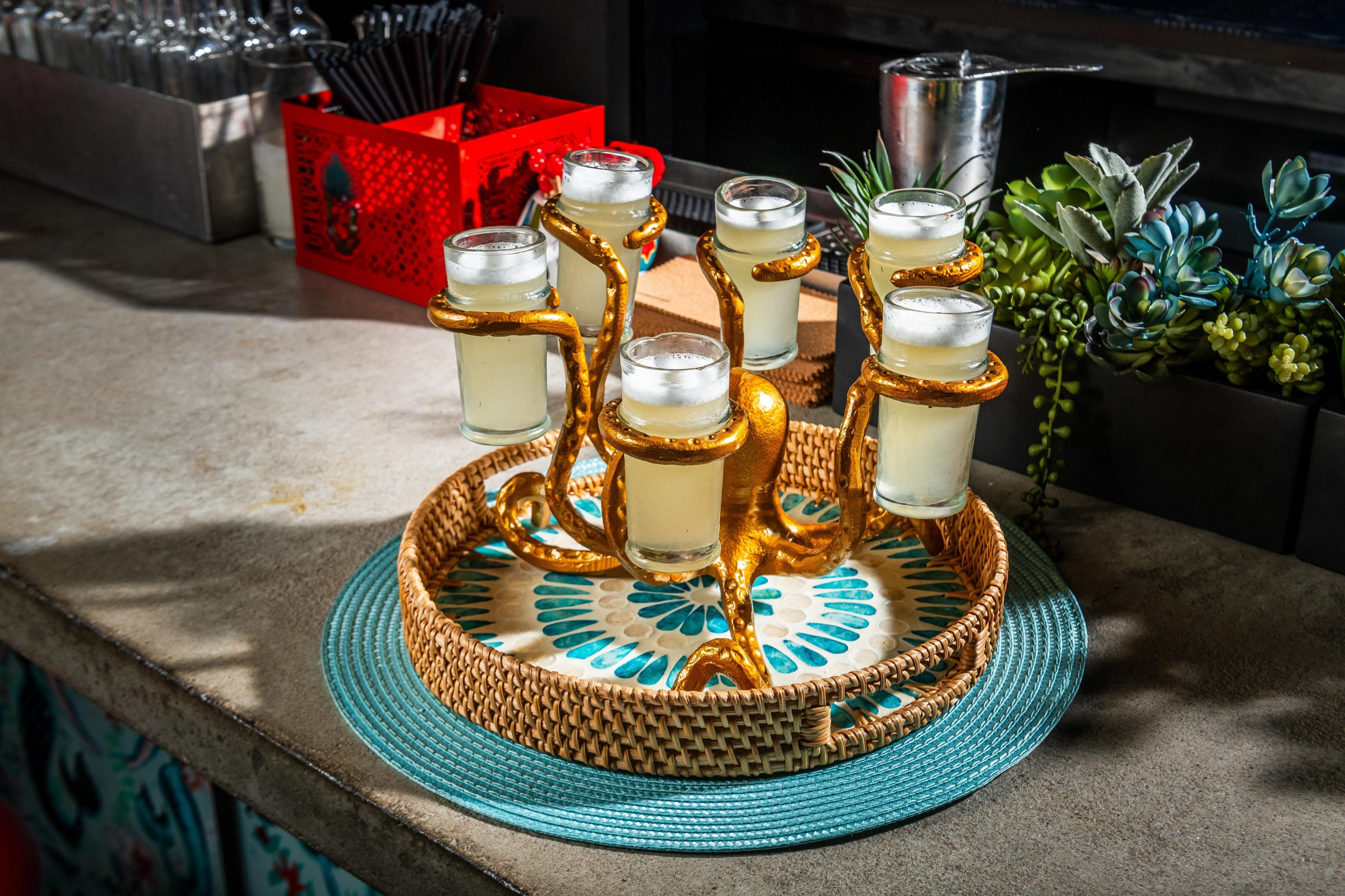A golden octopus presents a round of sugar cane daiquiris for six people.