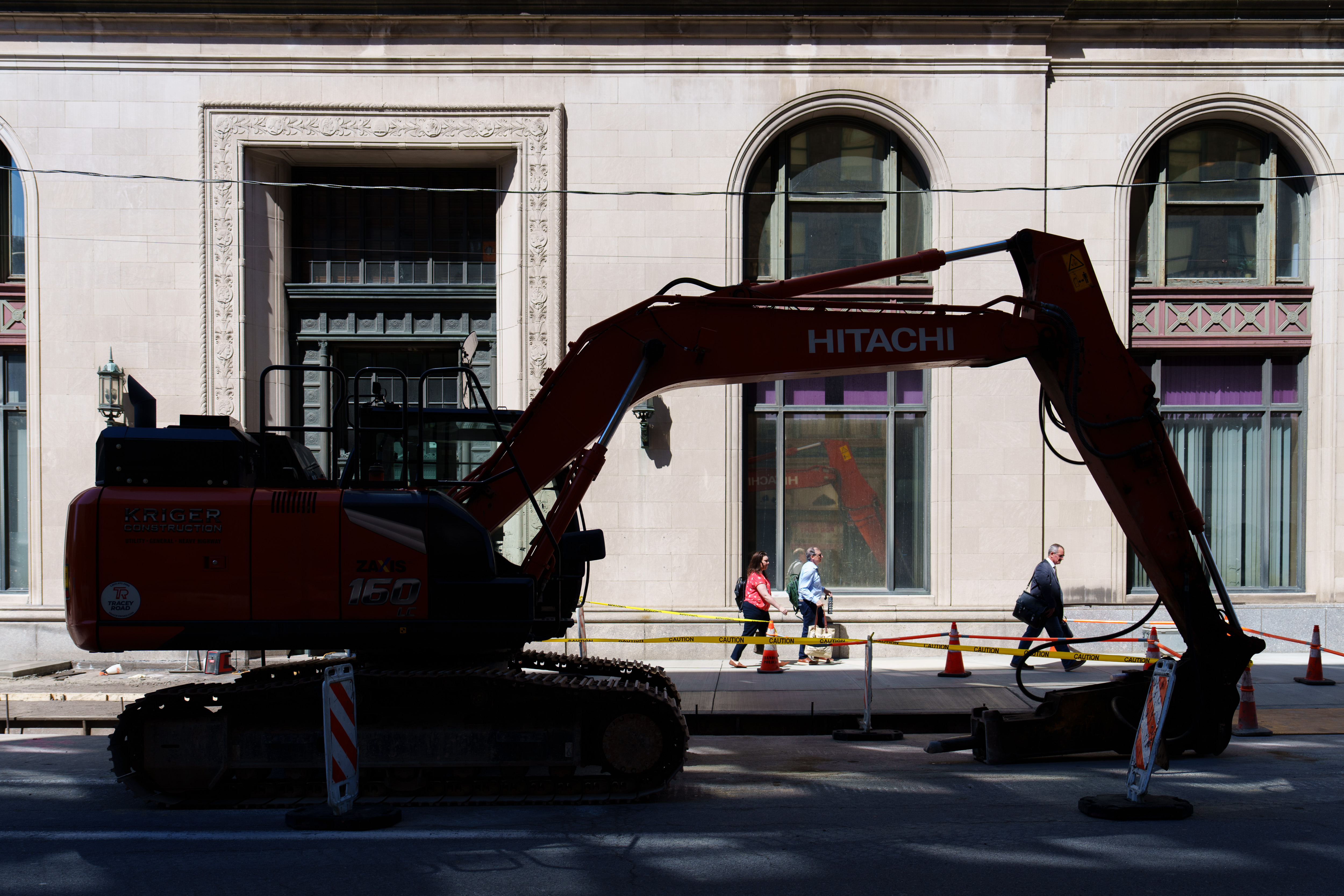 Pedestrians pass through a narrow section of sidewalk beneath an...