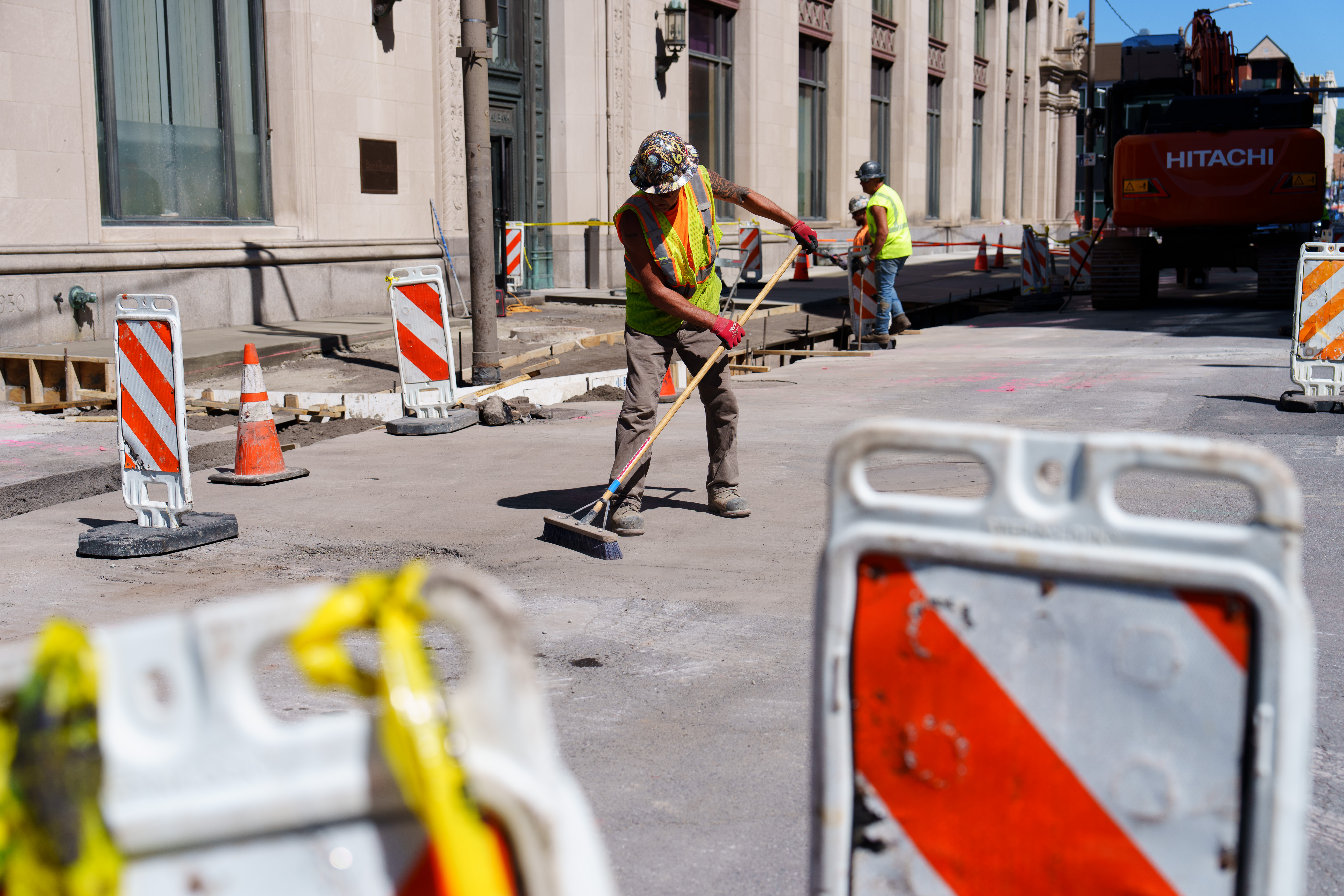 Mark Olson, a construction worker, sweeps debris from Biden Street...