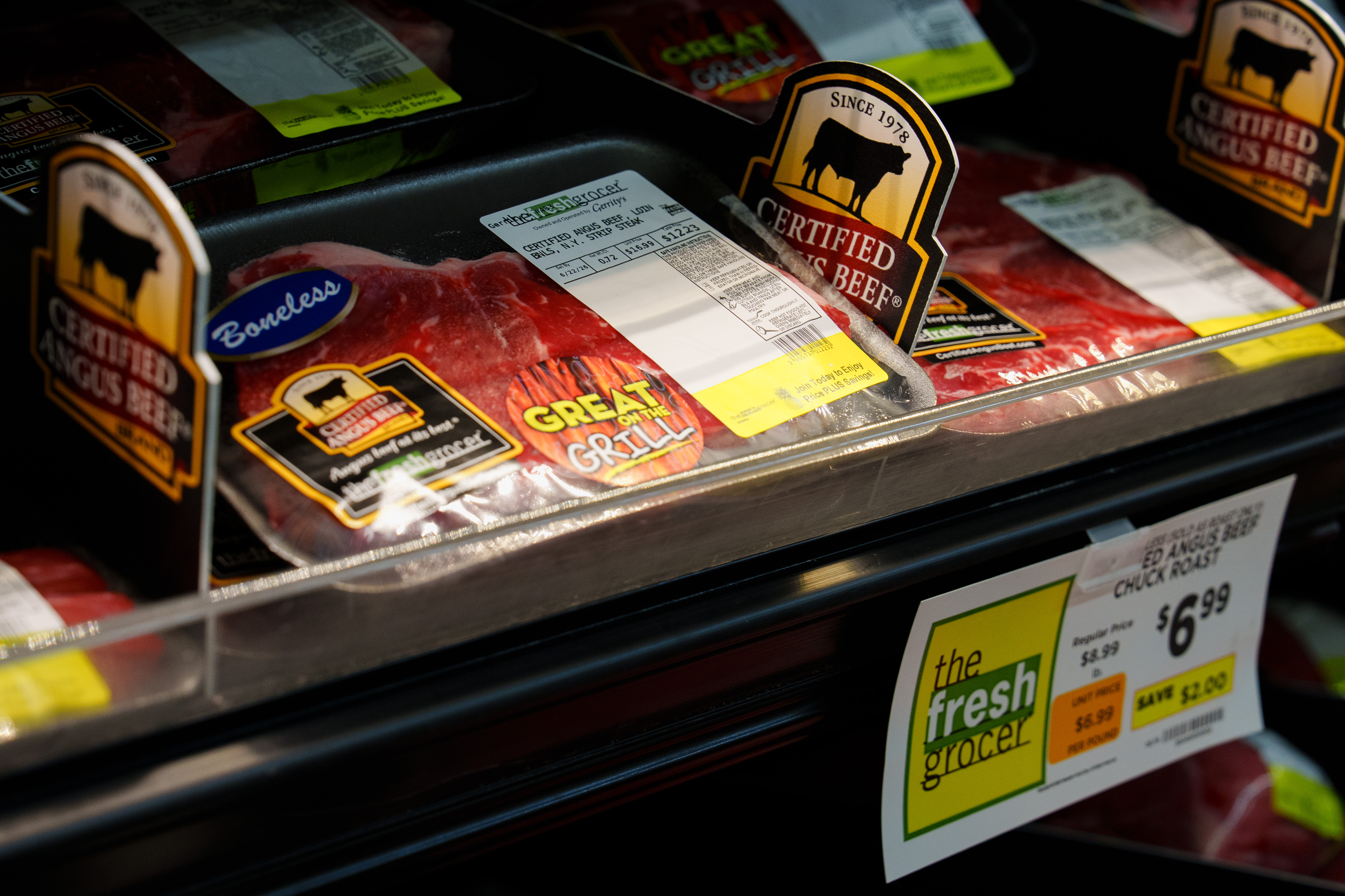 Packages of N.Y. strip steaks sit on a shelf in...