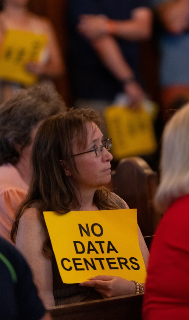 A woman holds a "NO DATA CENTERS" sign during a council meeting in the Municipal Building in Olyphant on Tuesday, June 9, 2026. (FRANK WILKES LESNEFSKY / STAFF PHOTO)