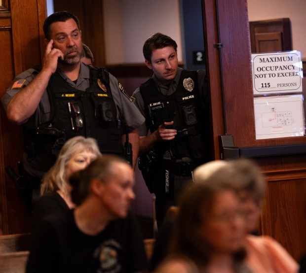 Olyphant Police Chief James DeVoe, left, and Officer Clayton DeVoe monitor a council meeting in the Municipal Building in Olyphant on Tuesday, June 9, 2026. (FRANK WILKES LESNEFSKY / STAFF PHOTO)