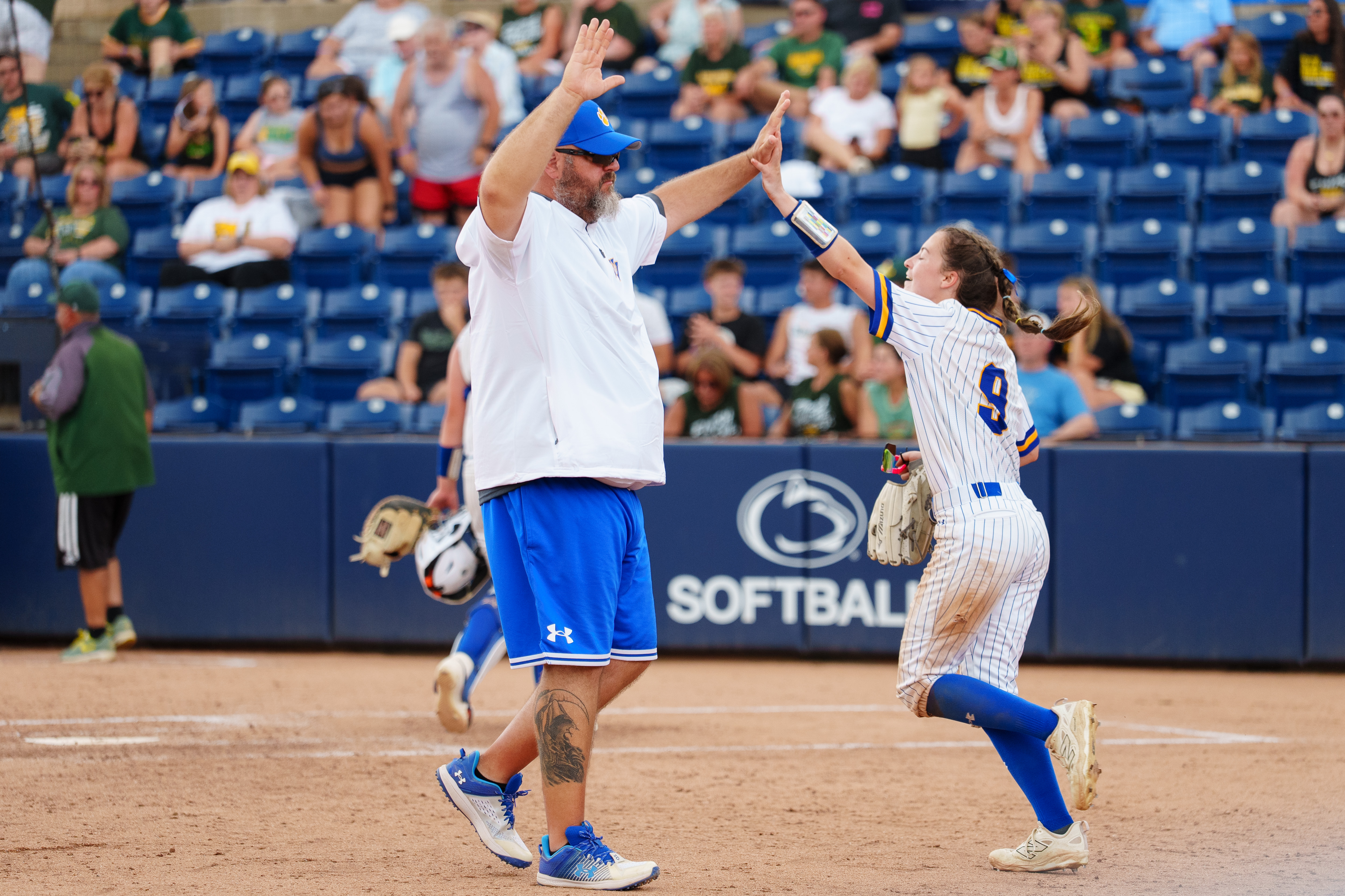 Assistant coach Justin Stevens high-fives players as they take the...