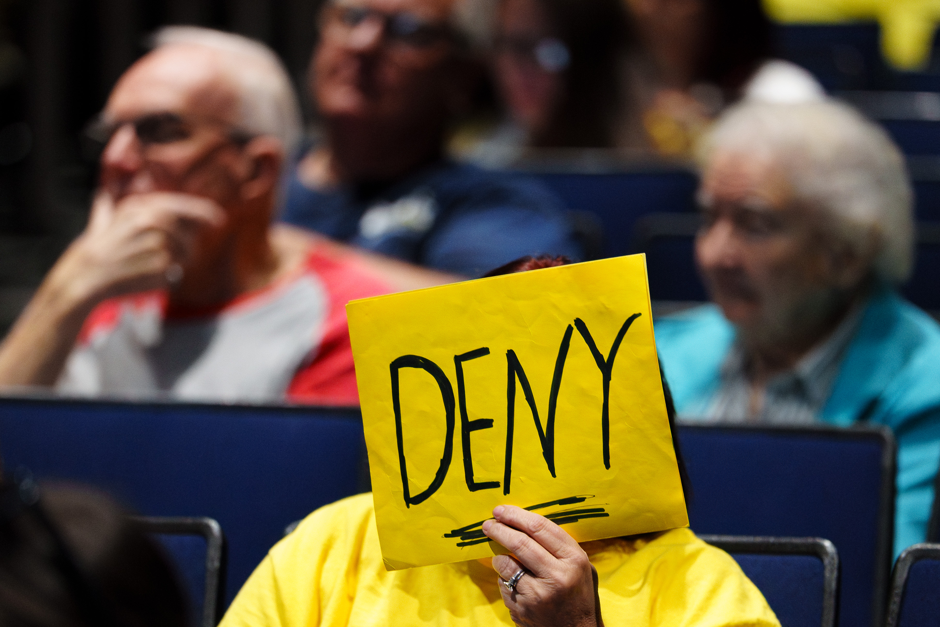 An attendee holds a sign reading “DENY” during a public...