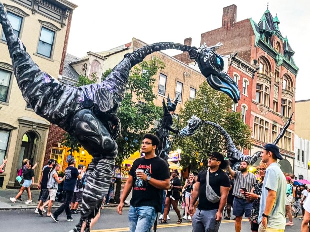 Faces in the crowd Sunday, Aug. 10, 2025, at MusikFest in Bethlehem. Saurus returns to Musikfest this year, with street performances. The Saurus performers are known for their theatrical flair and ability to engage with the audience. (Monica Cabrera/The Morning Call)
