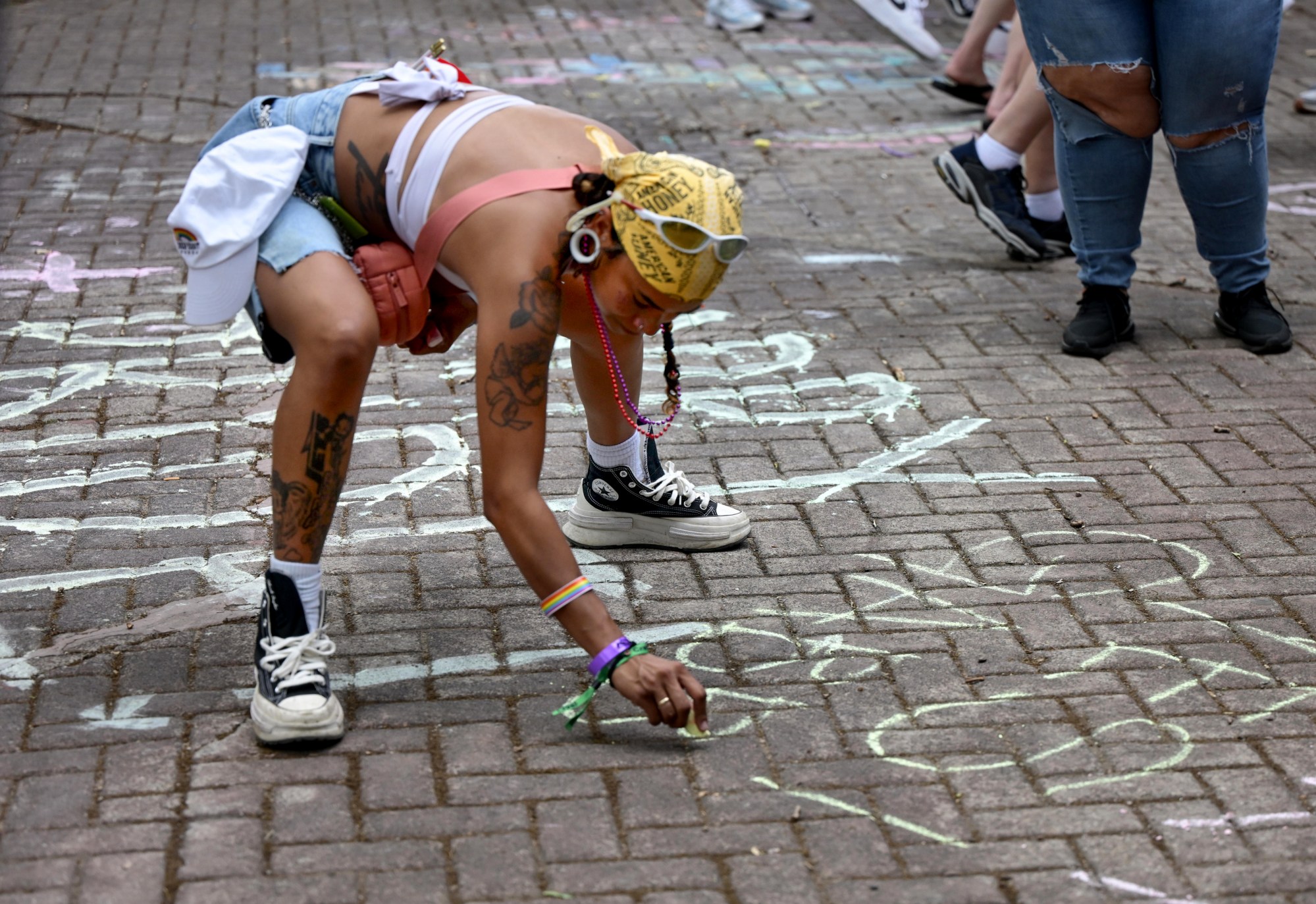 Gabriella Pastor writes in chalk Sunday, June 14, 2026, with friends at Pride Party Palooza at the Sun Inn Courtyard in Bethlehem. The afternoon event featured drag performances, music by DJ Brad Scott, vendors, and interactive entertainment. The Pride Party Palooza benefits the Eastern Pa Trans Equity Project. (Monica Cabrera/The Morning Call)