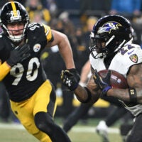 Jan 4, 2026; Pittsburgh, Pennsylvania, USA; Baltimore Ravens running back Derrick Henry (22) rushes the ball past Pittsburgh Steelers linebacker T.J. Watt (90) during the first half at Acrisure Stadium.