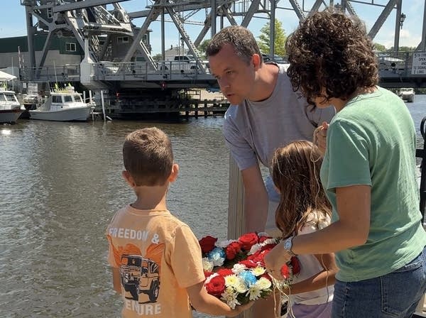 A pair of parents with their two children prepare to throw a memorial wreath into the Ashtabula harbor.