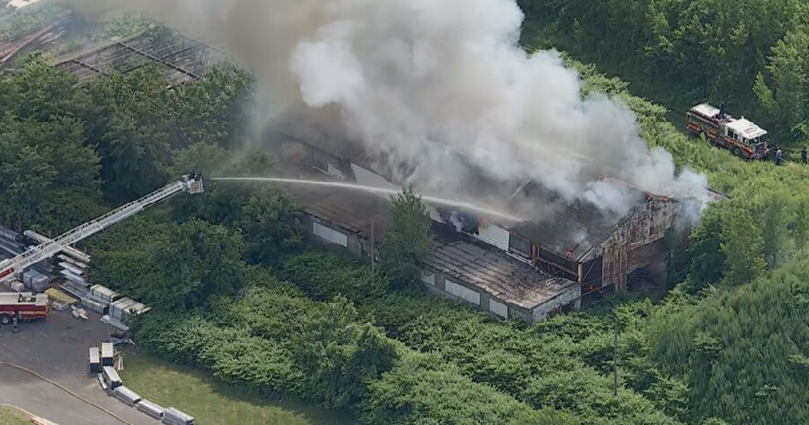 Smoke is seen coming from a warehouse in Camden, fire crews are shooting water