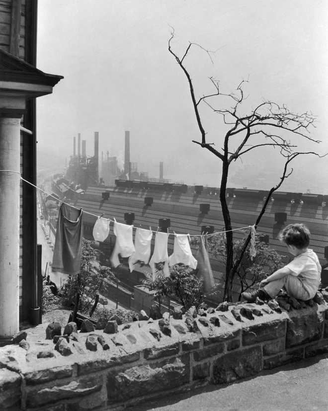 Pittsburgh View circa 1935: A young boy sits on a balcony overlooking a clothesline and a steel mill, Pittsburgh, Pennsylvania, 1930s. (Photo by Newman-Schmidt Studios/Getty Images)
