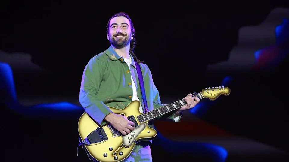Noah Kahan holds guitar on stage