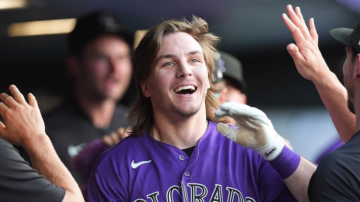 Colorado Rockies' Jake McCarthy returning to dugout after inside-the-park home run.