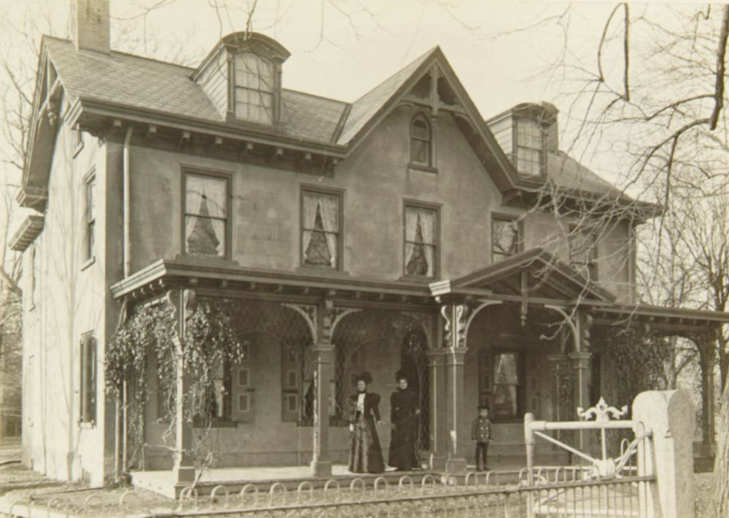 An archival photo of the Leibert House, with people standing on the front porch.